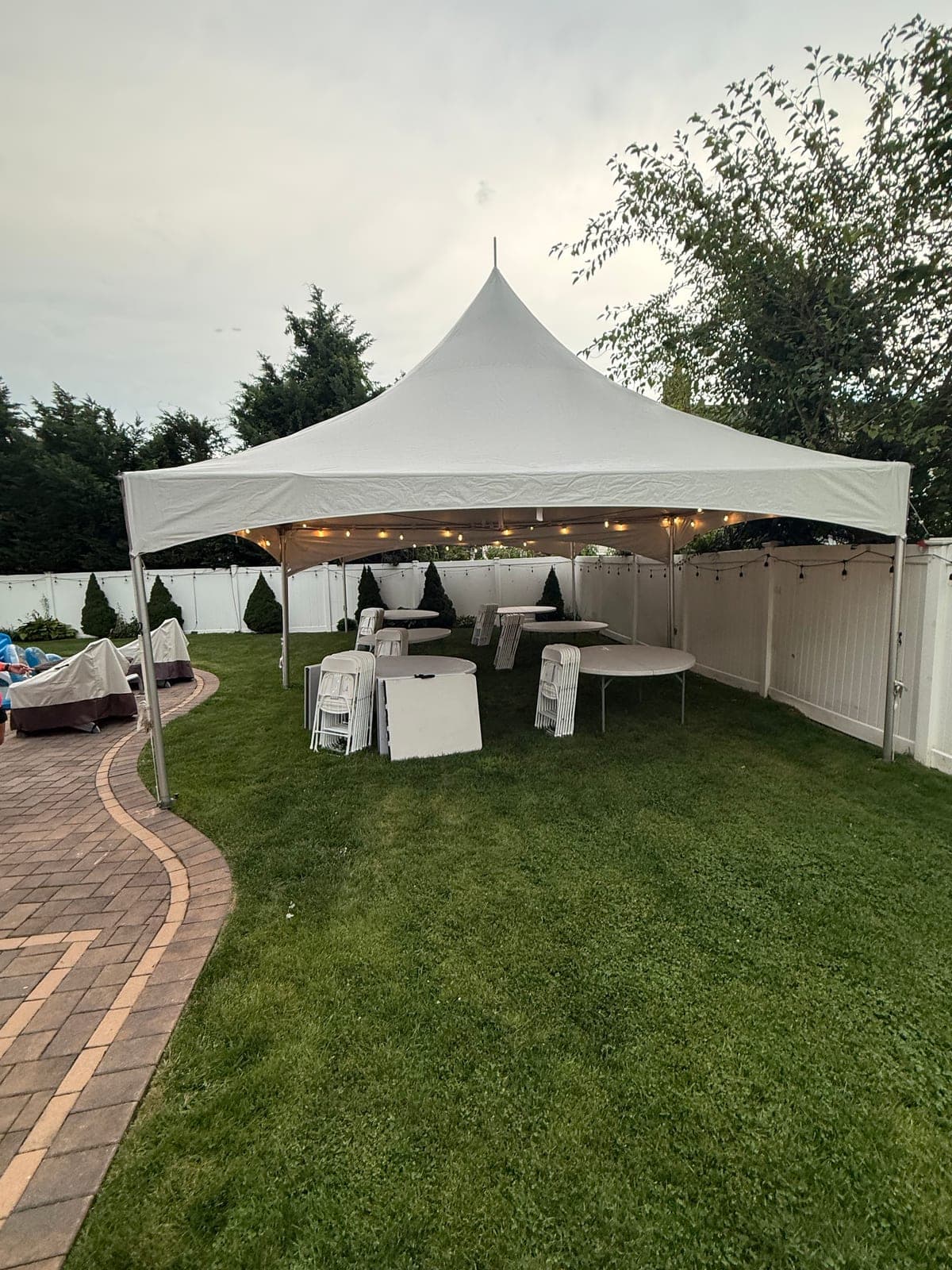 20 by 35 high-peak tent: 20×35 at dusk, lights on, tables going in